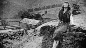 Still image from Helen of Four Gates. Black and white image of forlorn woman on Calderdale hillside with farm in the background